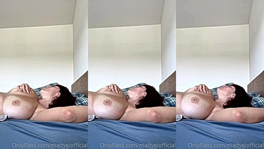Mady Gio playing with her naked big tits lying down in bed